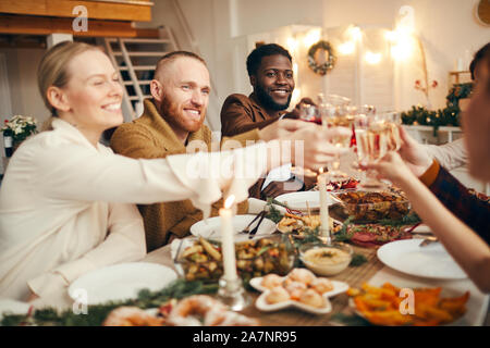 Multi-ethnischen Gruppe von Menschen erhöhen Gläser während wir Weihnachten feiern mit Freunden und Familie sitzt am wunderschönen Tisch Stockfoto