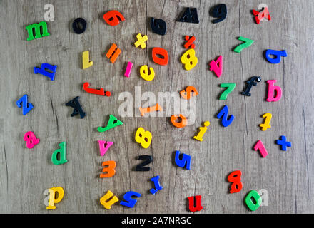 Direkt oberhalb der Schuß von mehreren farbigen Kunststoff Zahlen und Buchstaben auf dem Holztisch. Stockfoto
