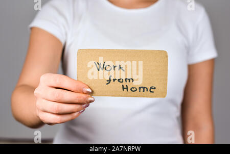Nahaufnahme von jungen Frauen Hand, die Pappe Papier mit Arbeit von zu Hause Phrase. Stockfoto