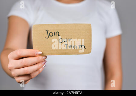 Nahaufnahme von jungen Frauen Hand, die Pappe Papier mit werden Sie Mitglied in unserem Team Satz Text. Stockfoto