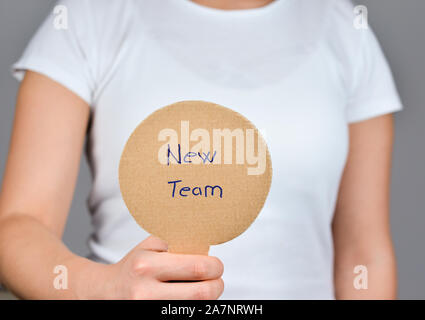 Frauen Hand mit Paddles Form Karton Papier hausgemachte mit handschriftlichen blauer Text - Neues Team Stockfoto