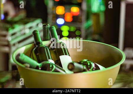 Flaschen Wein ungeöffnet in eine Edelstahl goldenes Bügeleisen Schüssel bei einer Party-Ereignis auf einem Defokussierten grüne Lichter Hintergrund. Stockfoto