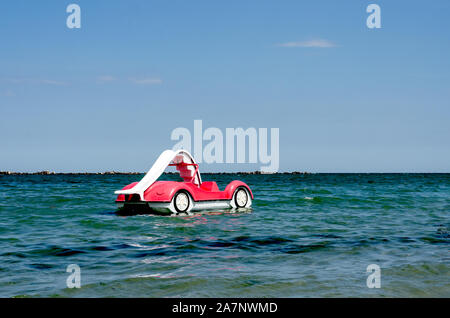 Spaß und aktive Spiele für ältere Menschen und Kinder am Strand zu spielen. Strand paddeln rot Boote während der Sommersaison an der Küste geparkt bereit, Stockfoto