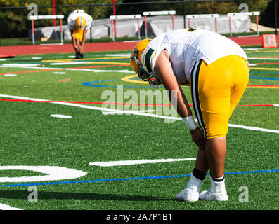 Zwei High School Football spieler Stretching auf grünem Rasen Feld vor dem Spiel beginnt an einem sonnigen Samstag Nachmittag. Stockfoto