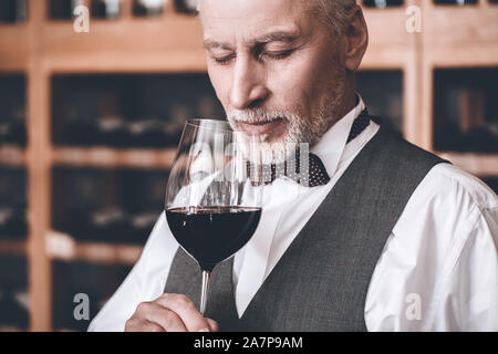 Sommelier Konzept. Älterer Mann stand halten Glas Wein riechen geschlossenen Augen freudige close-up Stockfoto
