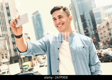 Freizeitaktivitäten im Freien. Stilvolle Kerl stehen auf der Straße unter selfie lächelt Fröhlich Stockfoto