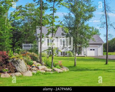 Blick auf die Straße von einem malerischen Landhaus mit einem großen gepflegten Vorgarten in einer waldreichen ländlichen Gebiet in den östlichen Gemeinden von Quebec, Kanada. Stockfoto