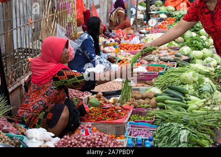 Labuanbajo, Indonesien - 17. August 2015: Eine Frau wird den Verkauf von Gemüse auf einem Straßenmarkt in Labuanbajo Stockfoto