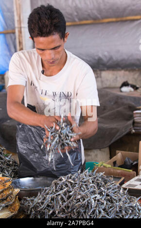 Labuanbajo, Indonesien - 18. August 2015: Indonesischer Mann Verkauf von getrockneten Fisch auf dem Markt Stockfoto