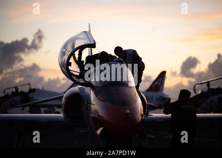 Us-Segler verhalten Preflight Checks auf einem T-45 C Goshawk Schulungsflugzeug, zur Ausbildung Air Wing (TW) 1, auf der Flight Deck des Flugzeugträgers USS John C Stennis (CVN 74) im Atlantischen Ozean, Okt. 31, 2019 zugeordnet. Die John C Stennis unterwegs ist die Durchführung von routinemäßigen Maßnahmen zur Unterstützung der Commander, Naval Air Force Atlantik. (U.S. Marine Foto von Mass Communication Specialist 3. Klasse Joshua L. Leonard) Stockfoto