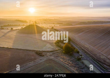 Silbury Hill, Nr Avebury, Wiltshire, UK. 28. Oktober 2019. Drone Bild von einem frostigen Roten morgen Himmel über dem alten künstlichen Erdhügel Silbury Hill. Stockfoto