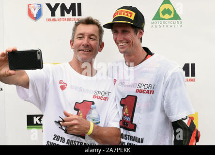 Mike Jones Anteile eine selfie mit Superbike- und MotoGP-Ducati Weltmeister Troy Bayliss auf das Podium der2019 Superbike Meisterschaft. Sydney, Australien Stockfoto