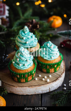 Mandarin Cupcakes mit festlich geschmückten Kappen von Butter Creme. Neues Jahr und Weihnachten Dessert. Stockfoto