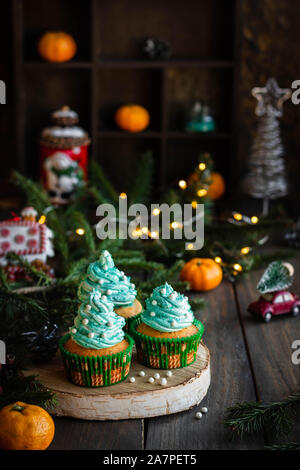 Mandarin Cupcakes mit festlich geschmückten Kappen von Butter Creme. Neues Jahr und Weihnachten Dessert. Stockfoto