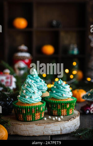 Mandarin Cupcakes mit festlich geschmückten Kappen von Butter Creme. Neues Jahr und Weihnachten Dessert. Stockfoto