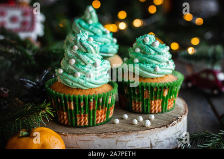 Mandarin Cupcakes mit festlich geschmückten Kappen von Butter Creme. Neues Jahr und Weihnachten Dessert. Stockfoto