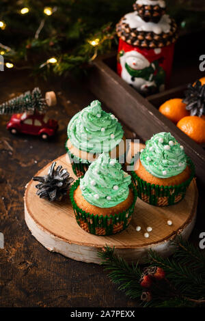 Mandarin Cupcakes mit festlich geschmückten Kappen von Butter Creme. Neues Jahr und Weihnachten Dessert. Stockfoto