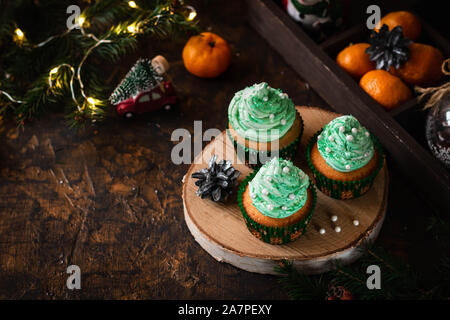 Mandarin Cupcakes mit festlich geschmückten Kappen von Butter Creme. Neues Jahr und Weihnachten Dessert. Stockfoto