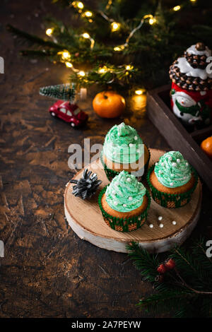 Mandarin Cupcakes mit festlich geschmückten Kappen von Butter Creme. Neues Jahr und Weihnachten Dessert. Stockfoto