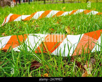 Grenze gestreift Ribbon auf grünem Gras. Hintergrund. Für Text platzieren. Stockfoto
