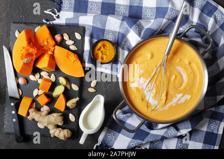 Cremige geröstete Kürbis Suppe in einem Topf auf einer konkreten Tabelle, Zutaten auf eine Tabelle, Ansicht von oben, flatlay Stockfoto