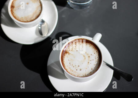 Frisch Gebrühter Cappuccino in Demitasse Cups. Overhead-Ansicht des Kaffees auf dem dunklen Hintergrund. Stockfoto