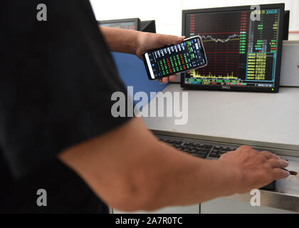 Ein Chinesischer Investor zeigt sein Smartphone angezeigte Preise der Aktien (rot für Preis steigt und grün für den Preis fallen) auf einer Börse brokerage House in F Stockfoto