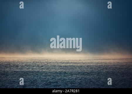 Meer Sonnenaufgang und nebliger Morgen. Nebel über blauen Wellen Wasser, Luftbild. Stockfoto