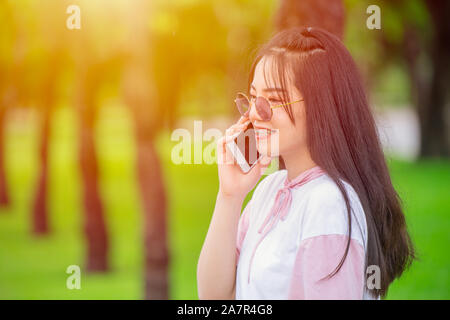 Mädchen jugendlich auf dem Smartphone Aufruf sprechen glückliches Lächeln grün outdor Natur Hintergrund. Stockfoto