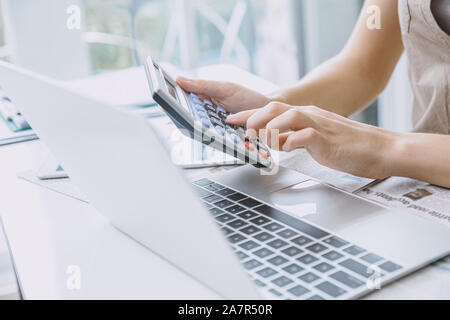 Closeup Mädchen Hand des Arbeiters Buchhalter mit Taschenrechner arbeiten im Büro Schreibtisch mit Laptop. Stockfoto