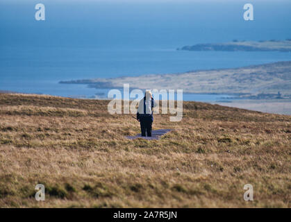 Ein einsamer Wanderer auf der Promenade in Hermaness auf der Insel Unst in Shetland, Schottland, Großbritannien. Die Küstenlinie der Insel ist im Hintergrund. Stockfoto