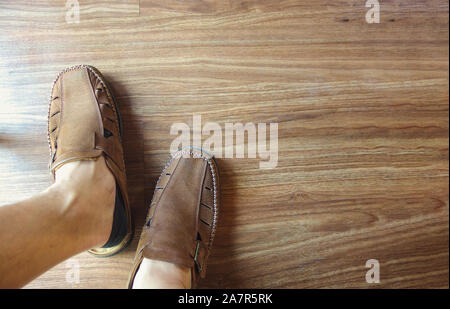 Man Fuß legere Schuhe aus Leder mit Holzboden Hintergrund. Stockfoto