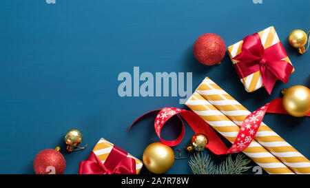 Weihnachtsschmuck, Geschenkpapier, Geschenkverpackung mit rote Schleifen, Bälle, Fir Tree Branch auf blauem Hintergrund. Flach, Ansicht von oben. Xmas banner Mockup, Neue Stockfoto