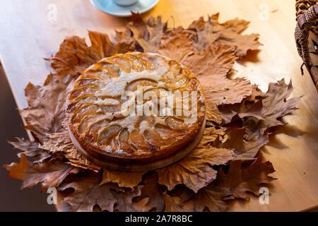 Frisch gebackene hausgemachten Apfelkuchen mit einer Tasse Tee in der Nähe von Korb mit Äpfeln auf Holztisch und Herbst gelb und rot Laub. Stockfoto