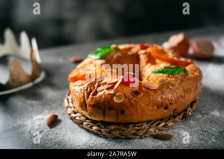 Nahaufnahme eines roscon de Reyes, drei Könige Kuchen auf epiphanie Tag gegessen Spanisch, auf einem grauen rustikalen Tisch Stockfoto