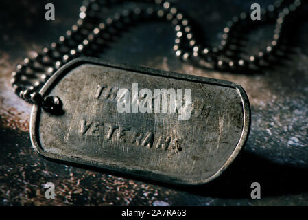 Nahaufnahme von einem rostigen Dog Tag mit dem Text Vielen Dank Veteranen in Es geschrieben, auf einem urigen graue Oberfläche Stockfoto