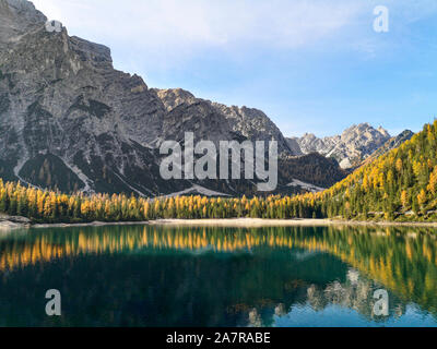 Italien, Trentino Alto Adige: die natürliche Landschaft der Pragser See mit grünen Bäumen, See mit Reflexion und Berg mit Schnee Stockfoto
