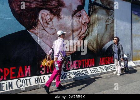 Berliner Mauer East Side Gallery, asiatische Touristen unter erschreckendem Kuss Breschnew Honecker Deutschland Europa Stockfoto