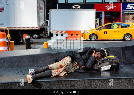 New York, USA - Juni 6, 2019: Schwarze Frau liegend auf der Steinbank in New York Time Square, Manhattan. Stockfoto