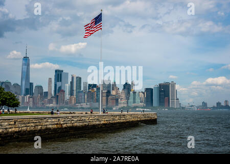 New York, USA - Juni 7, 2019: Amerikanische Flagge auf Liberty Island im Hafen von New York und Manhattan Skyline Stockfoto