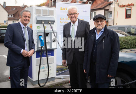 04 November 2019, Baden-Württemberg, Bad Urach: Frank Mastiaux (L-R), Vorstandsvorsitzender der EnBW, Winfried Kretschmann (Bündnis 90/Die Grünen), Ministerpräsident von Baden-Württemberg und Winfried Hermann (Bündnis 90/Die Grünen), Minister für Verkehr des Landes Baden-Württemberg, stand neben der Ladestation sind während einer Foto-session am Ende der 'SAFE' Projekt für den Bau von elektrischen Auto Ladestationen. Fahrer von Elektroautos können jetzt mit einem flächendeckenden Netz von mehr als 450 Ladestationen im Südwesten. Ein Konsortium aus EnBW, 77 Stadtwerke und Versorgungsunternehmen sowie Stockfoto