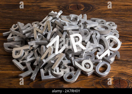 Stapel von silber Metall Alphabet mit waterjet machine-close-up View mit selektiven Fokus auf braunem Holz Hintergrund Stockfoto