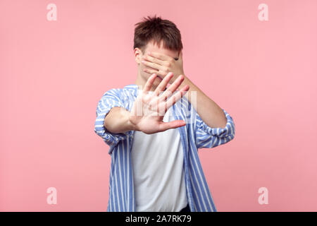 Möchten nicht an diesem zu suchen. Porträt der braunhaarige Mann in lässig-gestreiften Hemd, die Augen mit der Hand und nicht mehr angezeigt werden soll, Geste, die Ablehnung zu beobachten. Stockfoto