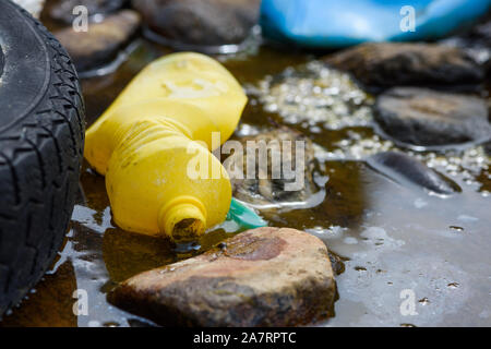 Plastikflaschen und Autoreifen in schlammigen ölhaltige Wasser, Strom Stockfoto