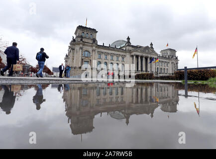 Berlin, Deutschland. 04 Nov, 2019. Menschen gehen vorbei an einer Pfütze von Regen vor dem Reichstag im Regierungsviertel, wo der Sitz des Deutschen Bundestages wider. Quelle: Wolfgang Kumm/dpa/Alamy leben Nachrichten Stockfoto