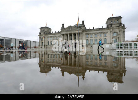 Berlin, Deutschland. 04 Nov, 2019. Menschen gehen vorbei an einer Pfütze von Regen vor dem Reichstag im Regierungsviertel, wo der Sitz des Deutschen Bundestages wider. Quelle: Wolfgang Kumm/dpa/Alamy leben Nachrichten Stockfoto