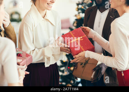 7/8-Portrait von eleganten jungen Menschen den Austausch von Geschenken während der Weihnachtsfeier, auf der Red Box mit Goldband konzentrieren, kopieren Raum Stockfoto