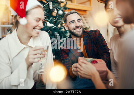 Portrait von eleganten erwachsenen Mann lächelt glücklich, während den Austausch von Geschenken mit Freunden während der Weihnachtsfeier Stockfoto