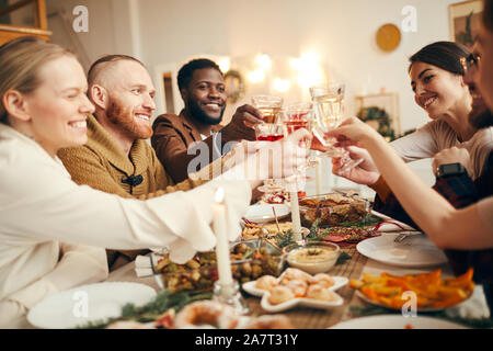 Multi-ethnischen Gruppe von Menschen erhöhen Gläser am schönen Abendessen sitzen wir Weihnachten feiern mit Freunden und Familie, kopieren Raum Stockfoto