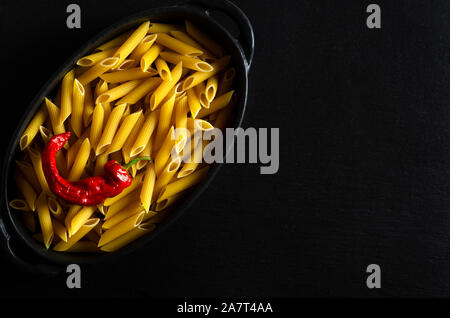 Nudeln mit getrockneten Chilischoten liegt in einem schwarzen Ovalen Backblech Stockfoto
